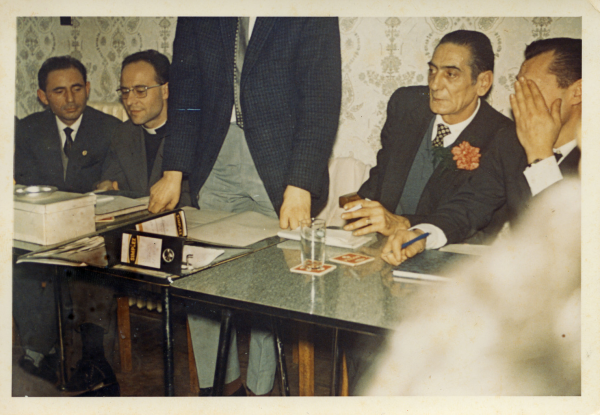 Vergadering van de Spaanse club Carlos Quinto met voorzitter Juan Ayestaran (tweede van rechts) en padre Rafael (tweede van links), s.d. Vergadering van de Spaanse club Carlos Quinto met voorzitter Juan Ayestaran (tweede van rechts) en padre Rafael (tweede van links), s.d.